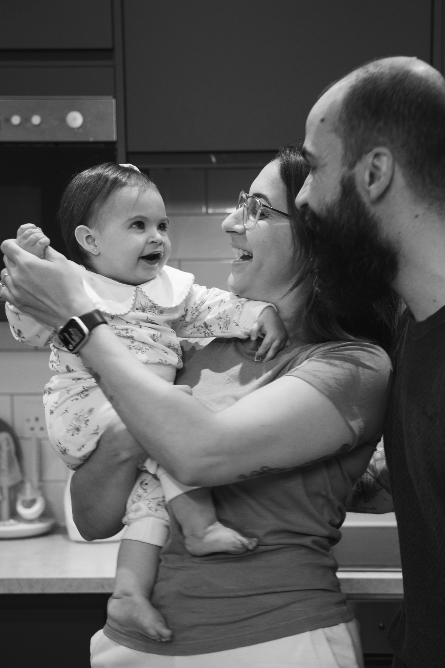 Pais sorrindo com sua bebê em um momento espontâneo em casa